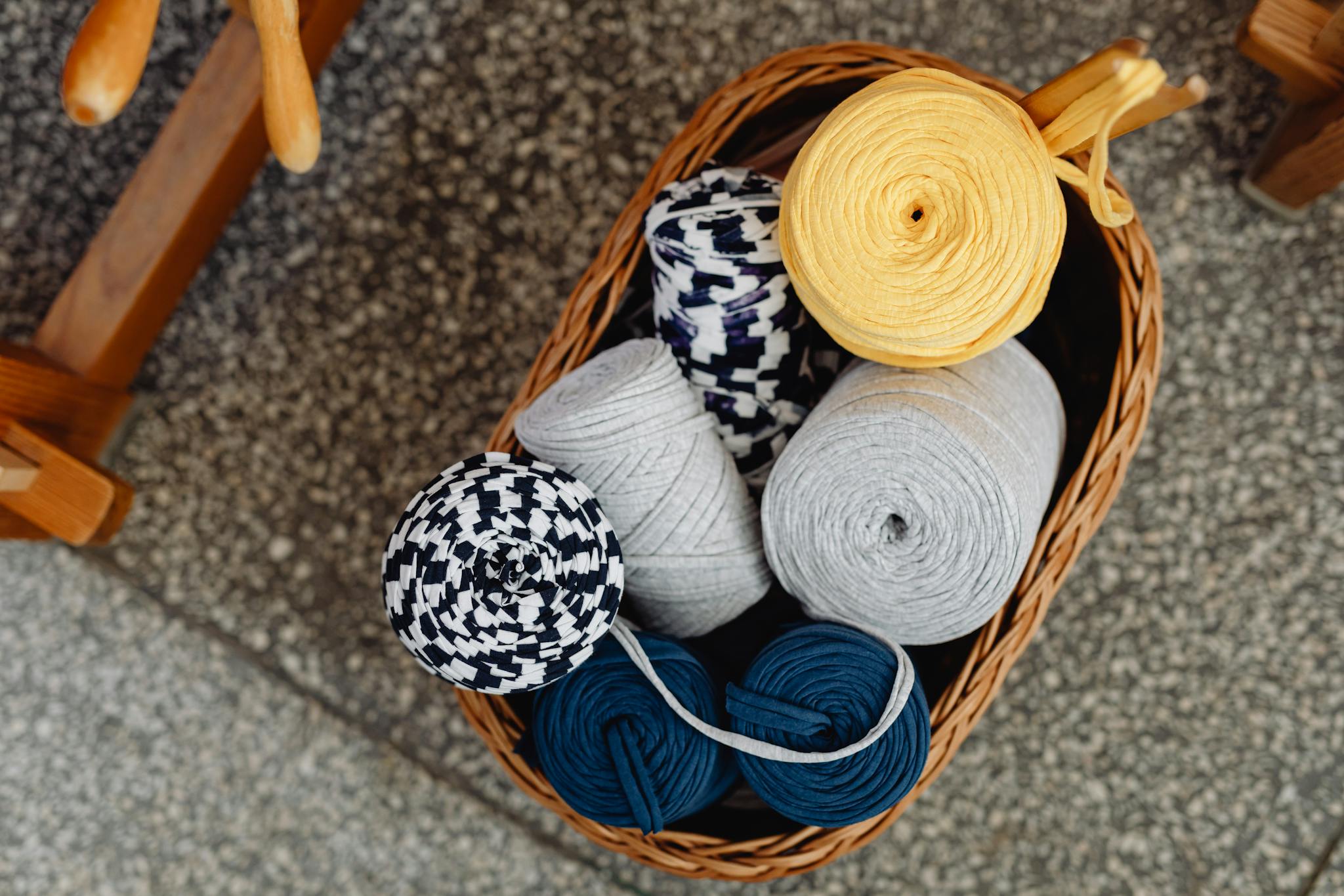 Top view of colorful yarn spools in a woven basket, ideal for crafting or knitting projects.